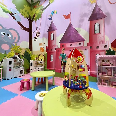 Evergreen Laurel Hotel - Тайчжун Экстерьер фото The photo shows a colorful children's playroom designed with a whimsical theme. The walls are painted in bright colors and feature a cartoon-style mural of a pink castle with purple towers and a smiling cartoon elephant. The room is filled with playf