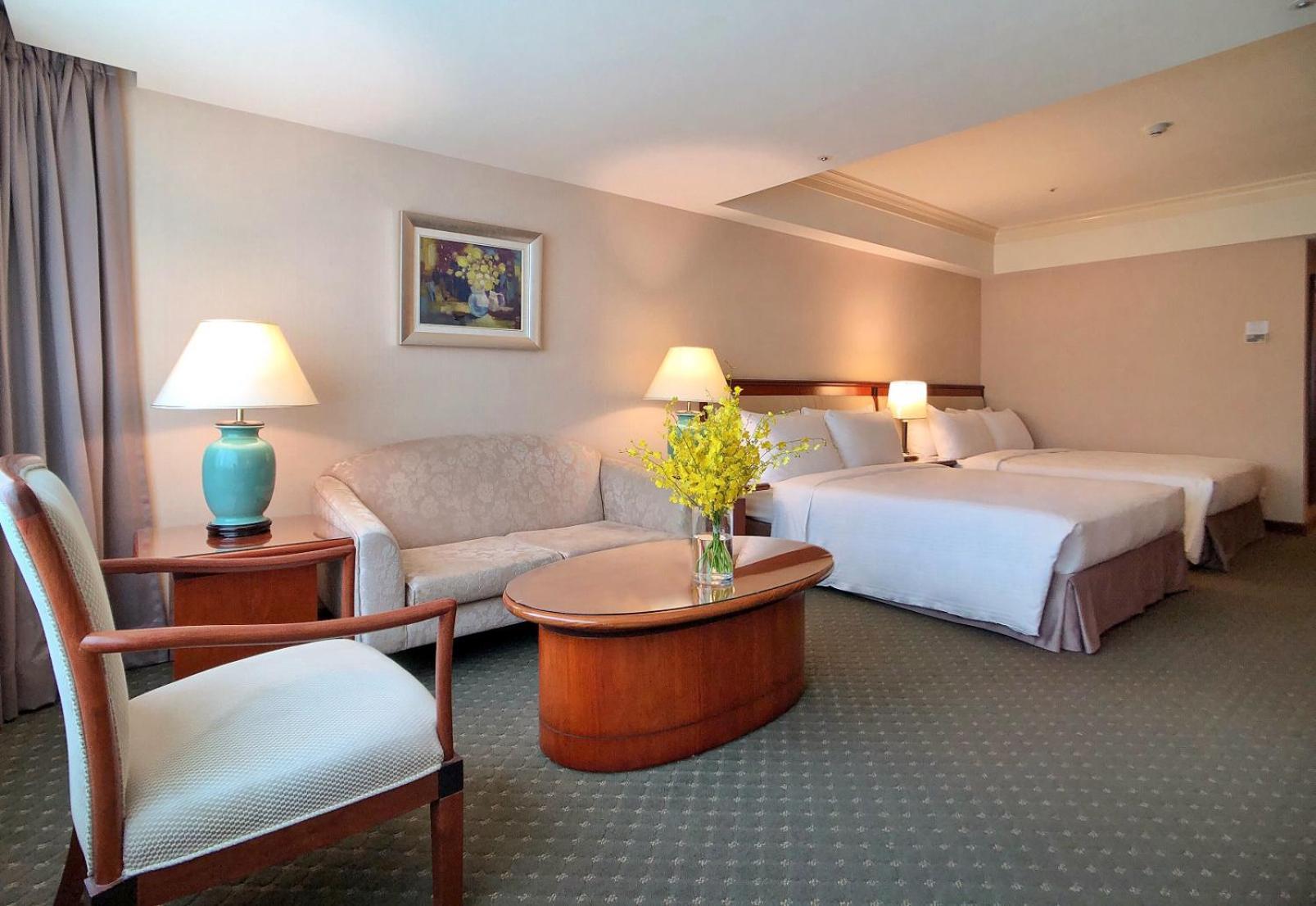 Evergreen Laurel Hotel - Тайчжун Экстерьер фото The photo shows a hotel room featuring two beds, a small seating area, and a coffee table. The walls are painted in soft, neutral colors, and there is a framed piece of artwork hanging on the wall. A potted plant with yellow flowers is placed on the 