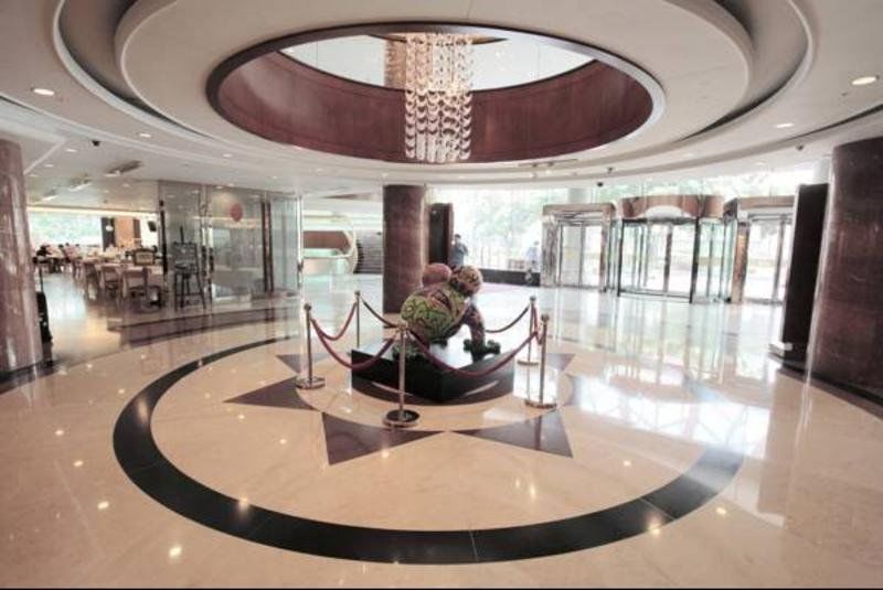Evergreen Laurel Hotel - Тайчжун Экстерьер фото The photo depicts an elegant indoor space, likely the lobby of a hotel or a building. The flooring is made of polished marble tiles, featuring a circular design with contrasting black and light-colored sections. At the center, there is a sculpture su