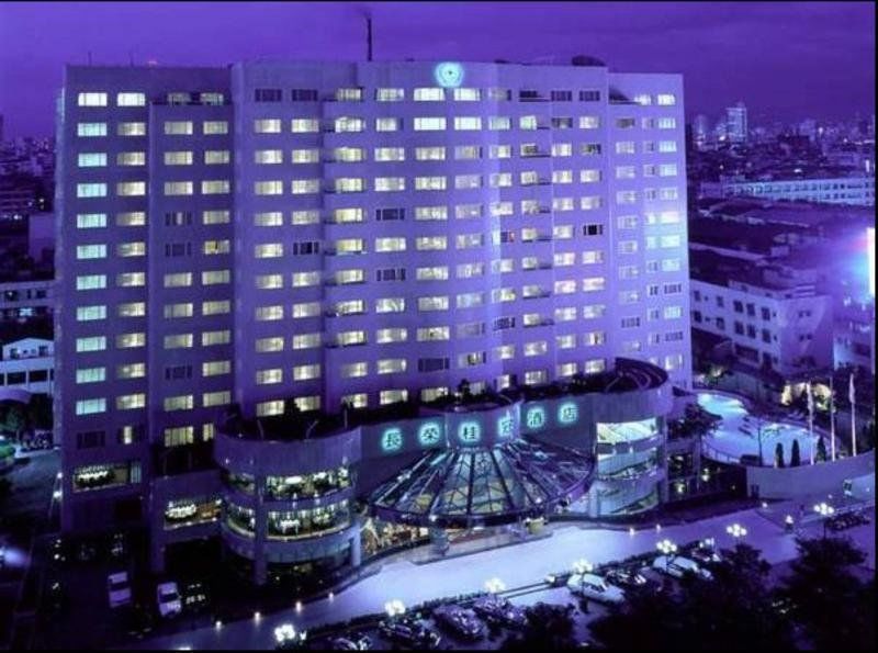 Evergreen Laurel Hotel - Тайчжун Экстерьер фото The photo shows a large hotel building illuminated in a purple hue during the evening or nighttime. The facade features numerous windows, many of which are lit, suggesting occupancy. The entrance area appears modern and curved, with a design that inc