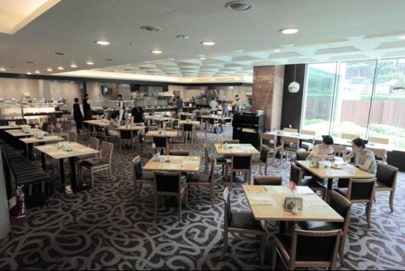Evergreen Laurel Hotel - Тайчжун Экстерьер фото The photo shows a spacious restaurant or dining area with a modern interior design. There are several tables arranged throughout the room, some of which are set for dining while others appear to be empty. The decor includes a patterned carpet and lar