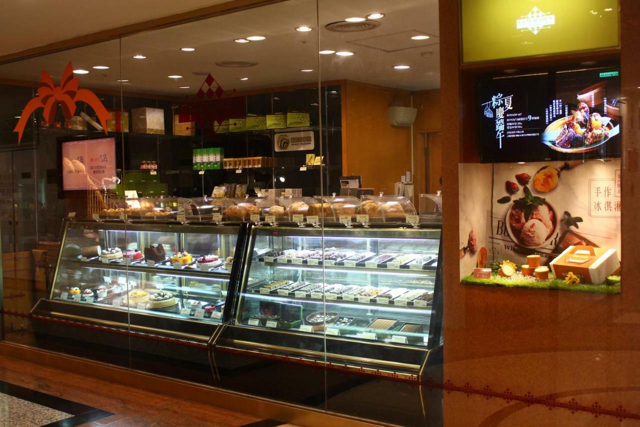 Evergreen Laurel Hotel - Тайчжун Экстерьер фото The photo shows a display case in a bakery or dessert shop. The glass case is filled with a variety of pastries, cakes, and desserts arranged neatly. Behind the display, there is a counter with additional items and desserts visible. The walls are dec