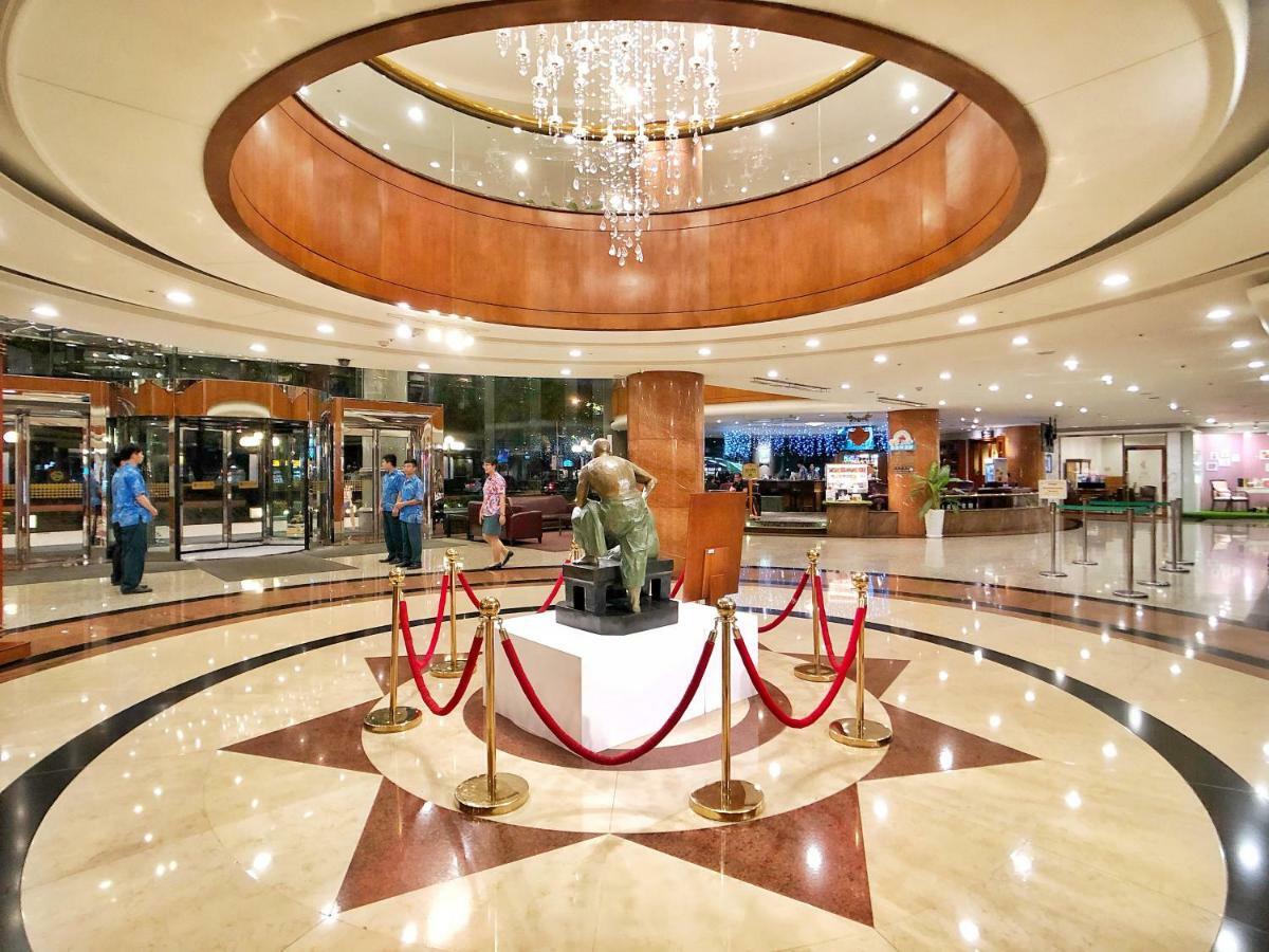 Evergreen Laurel Hotel - Тайчжун Экстерьер фото The image shows a spacious lobby area of a building, likely a hotel or an upscale establishment. The design features a circular ceiling with a chandelier hanging from it, creating a bright and elegant ambiance. At the center, there is a statue, likel