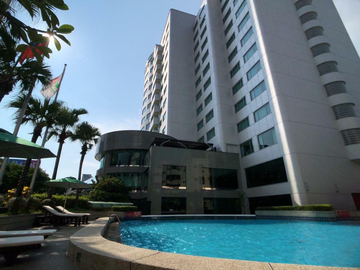 Evergreen Laurel Hotel - Тайчжун Экстерьер фото The photo depicts a hotel or residential building alongside a swimming pool. The pool is situated in the foreground, with a curved section of the building visible behind it. Surrounding the pool, there are lounge chairs for relaxation. In the backgro