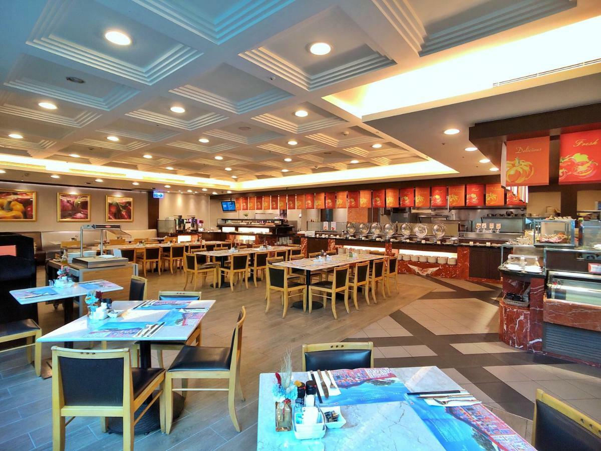 Evergreen Laurel Hotel - Тайчжун Экстерьер фото The photo shows the interior of a restaurant. The dining area features several tables with chairs arranged neatly. The flooring has a contemporary design, and the ceiling is structured with a coffered pattern. There is a buffet area along one wall wi