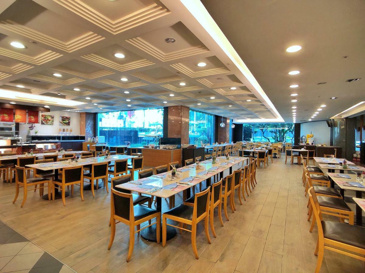 Evergreen Laurel Hotel - Тайчжун Экстерьер фото The photo shows the interior of a restaurant. It features a spacious dining area with several wooden tables and chairs arranged in rows. The floor has a light wood finish, complementing the stylish design. The ceiling is decorated with a modern patte